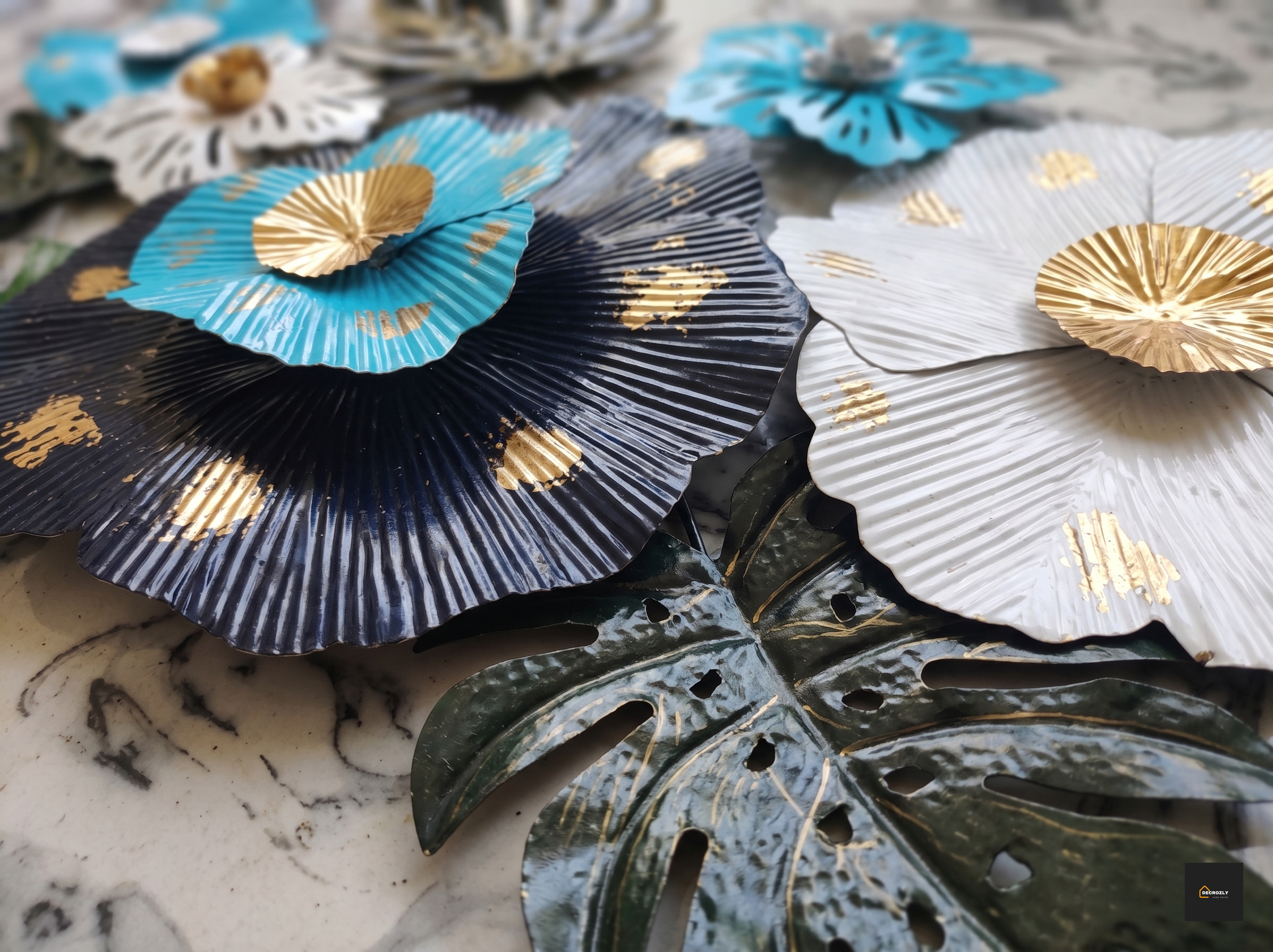 Decorative Metal wall art in blue, black, and white with gold accents on a marble surface.