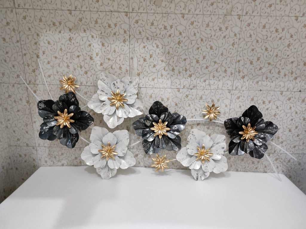 Decorative floral wall art with black, white, and gold flowers on a tiled wall.