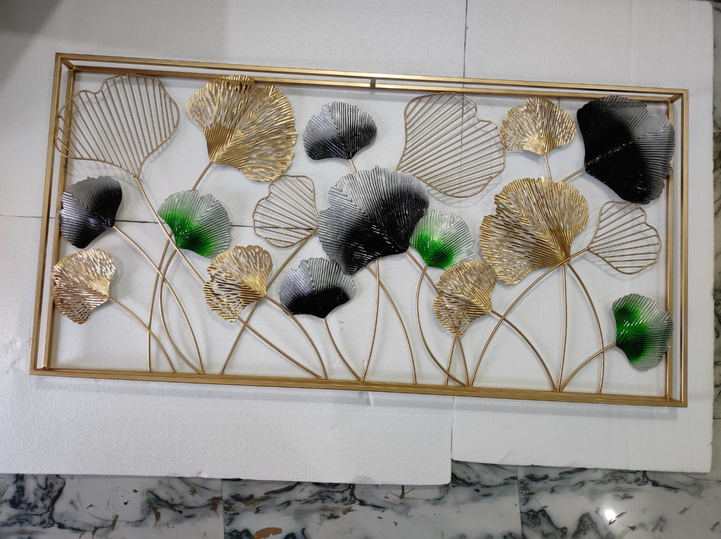Decorative wall art with gold, black, and green leaves on a marble surface